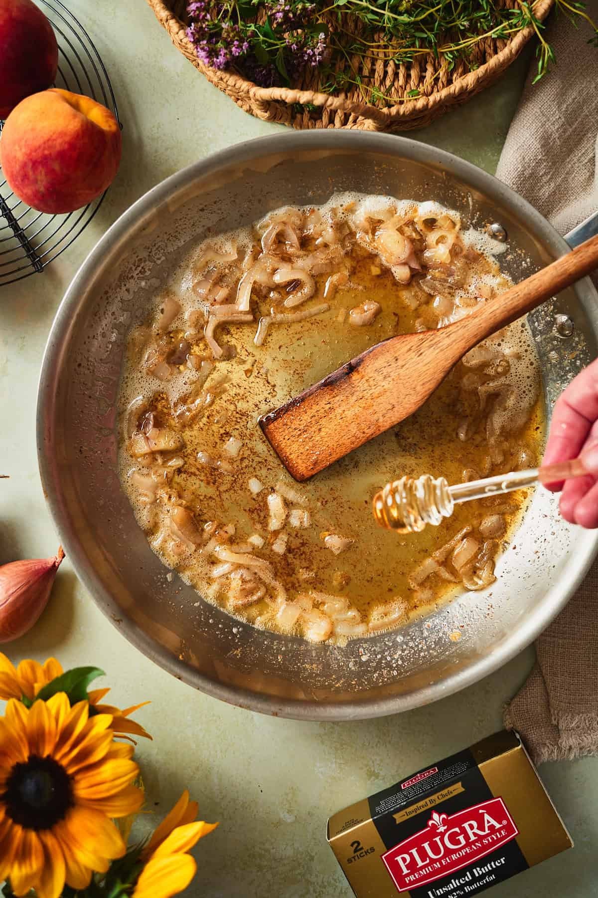 Honey drizzling into browned butter and shallots in a skillet.