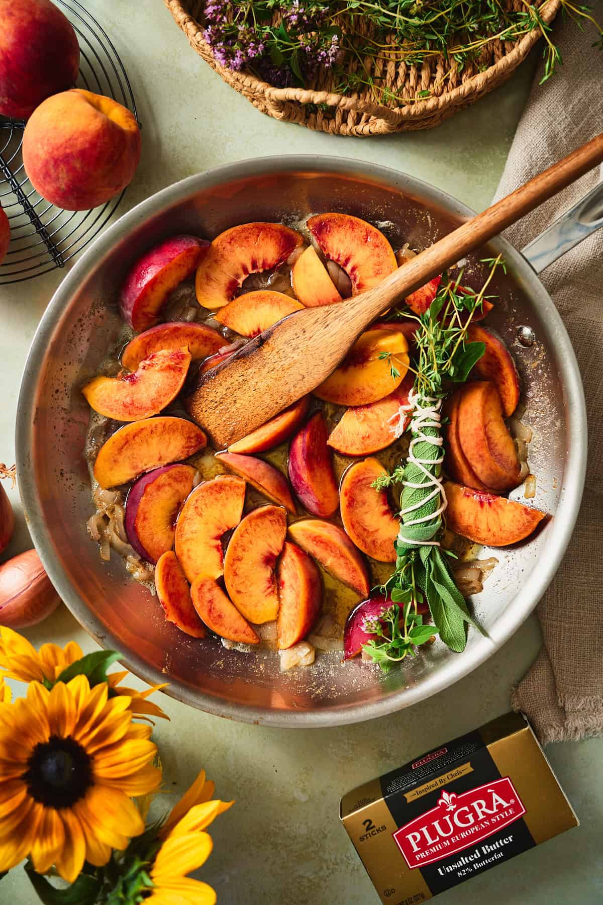 Fresh peach wedges and a tied herb bundle added to the buttery skillet.