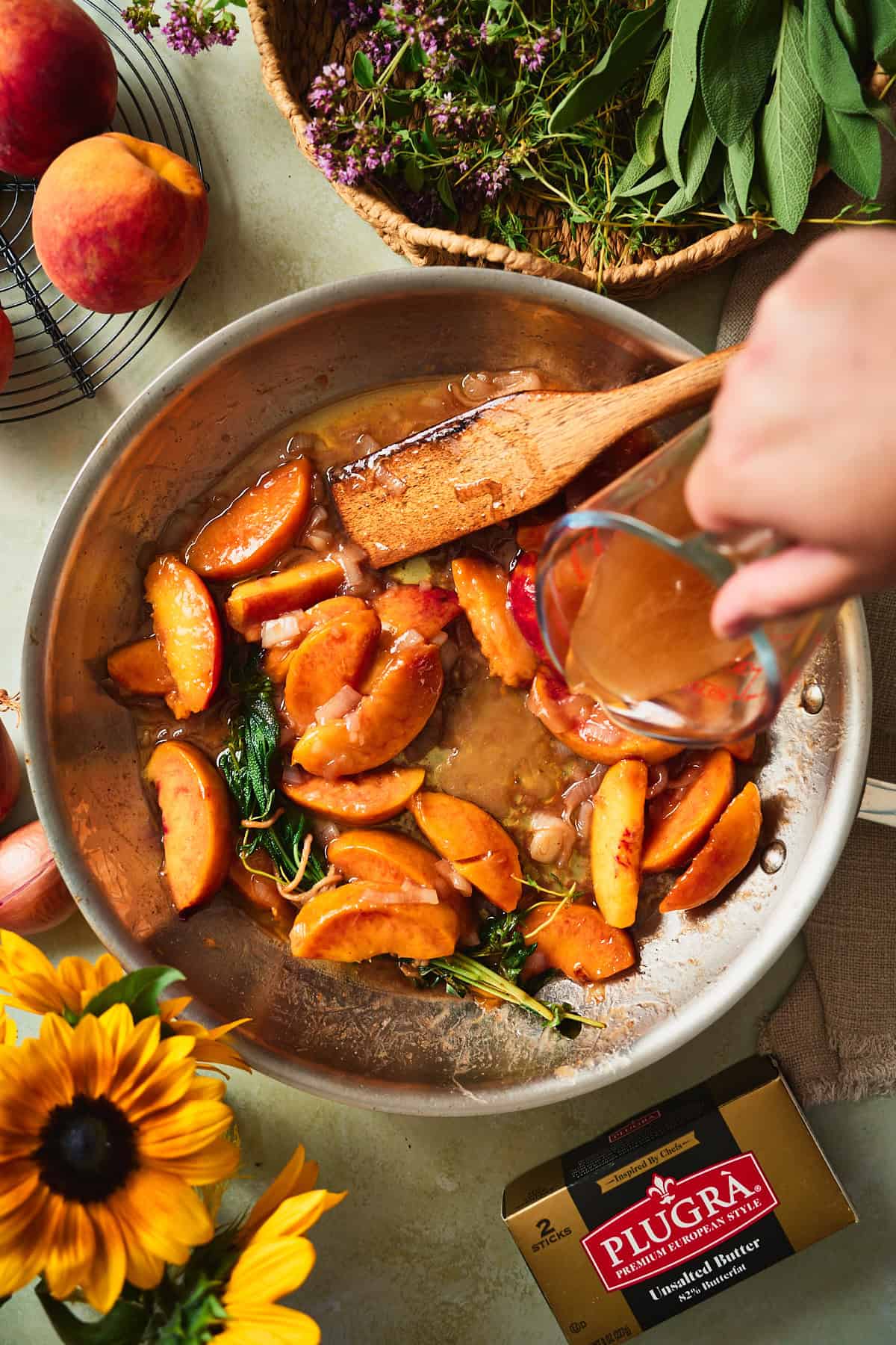 Chicken stock poured into a skillet of softened peaches and brown butter.