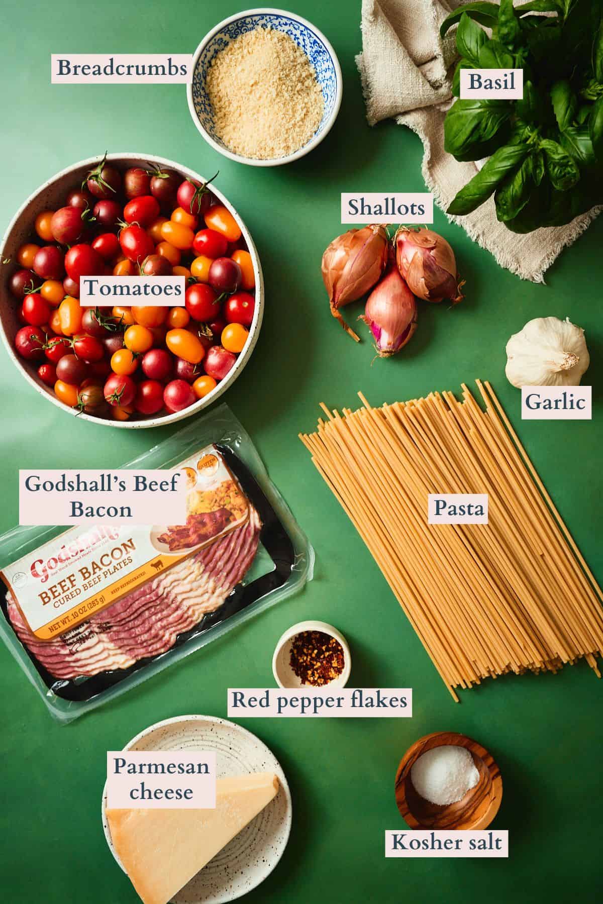 Labeled ingredients for bacon tomato pasta including cherry tomatoes, Godshall's beef bacon, bucatini, breadcrumbs, basil, shallots, garlic, Parmesan, and red pepper flakes.