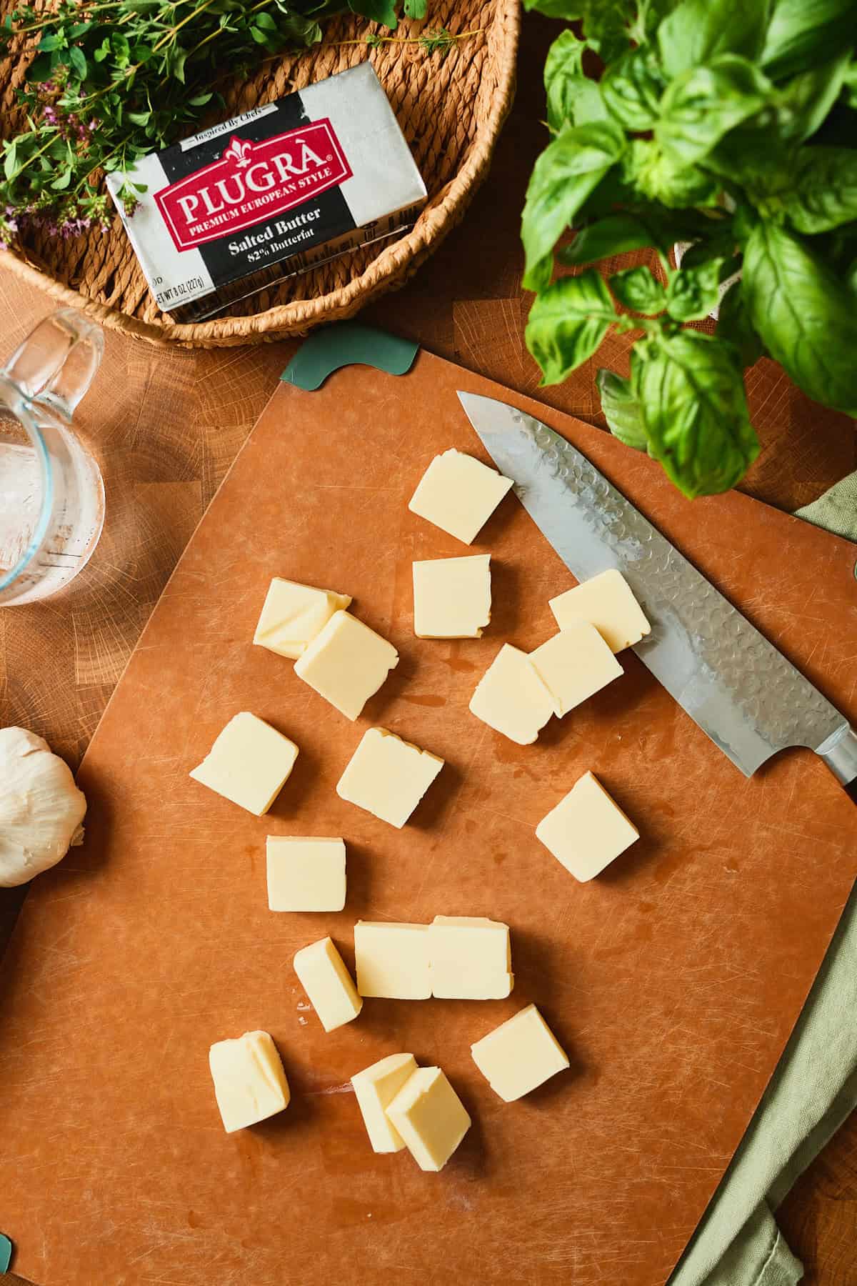 Cold Plugrà salted butter cut into cubes on a cutting board for an all-butter galette crust.
