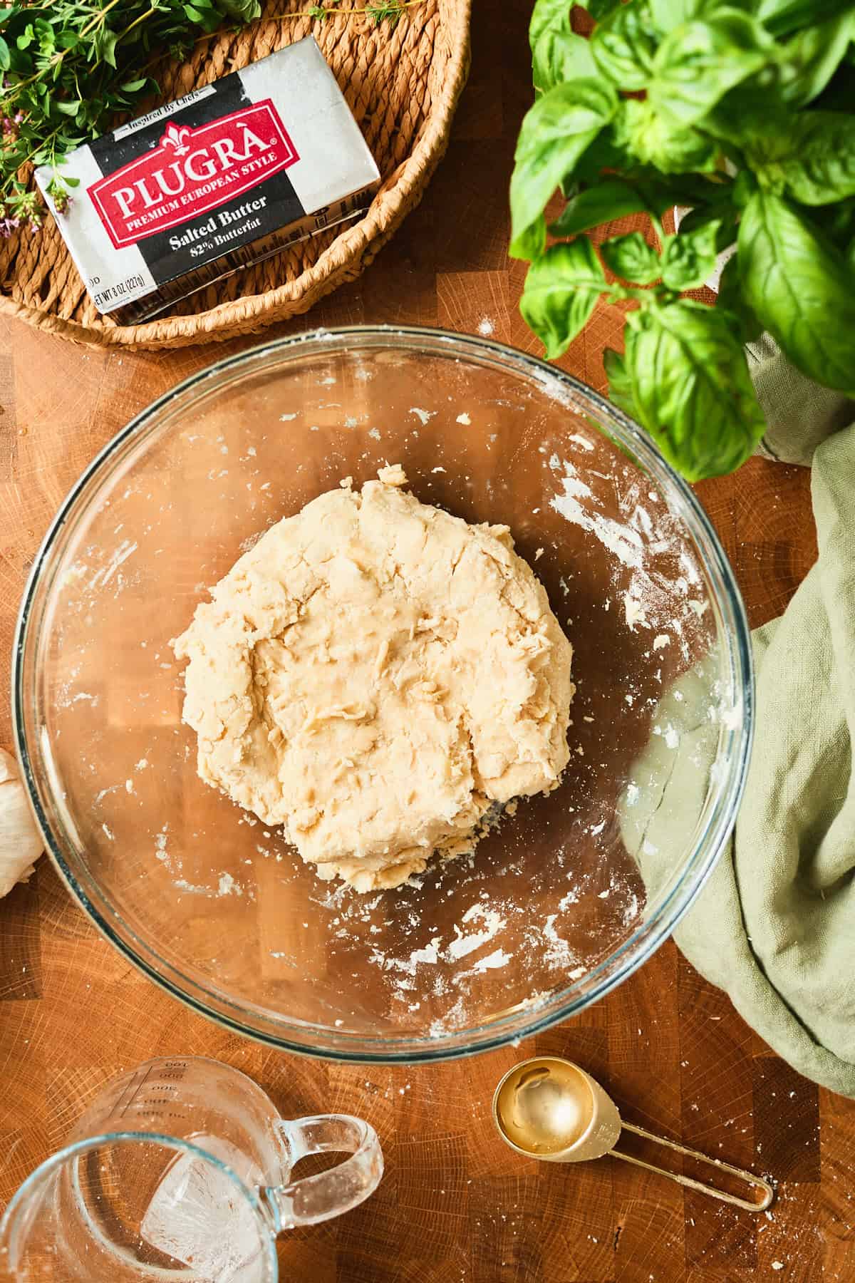 Galette dough gathered into a rough ball in a glass mixing bowl.