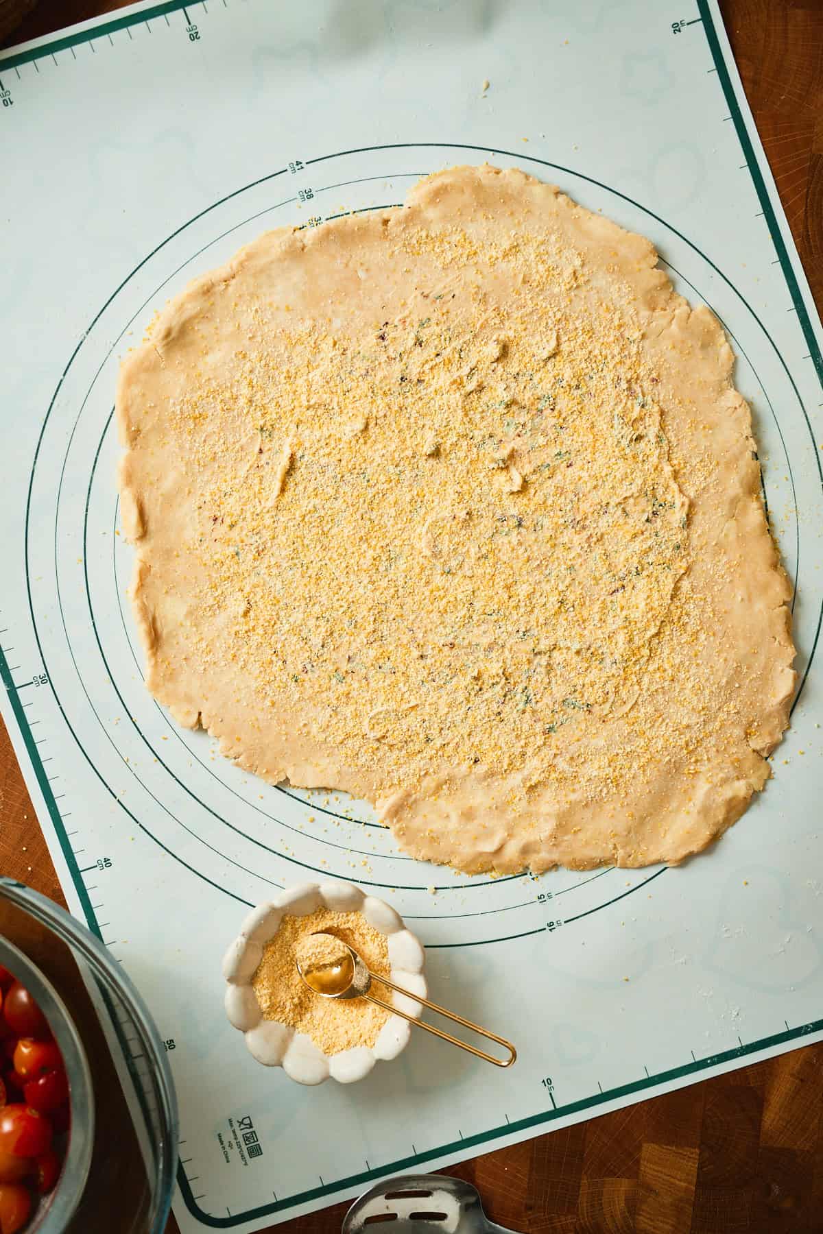 Cornmeal scattered over garlic herb butter on galette dough before the tomatoes go on.