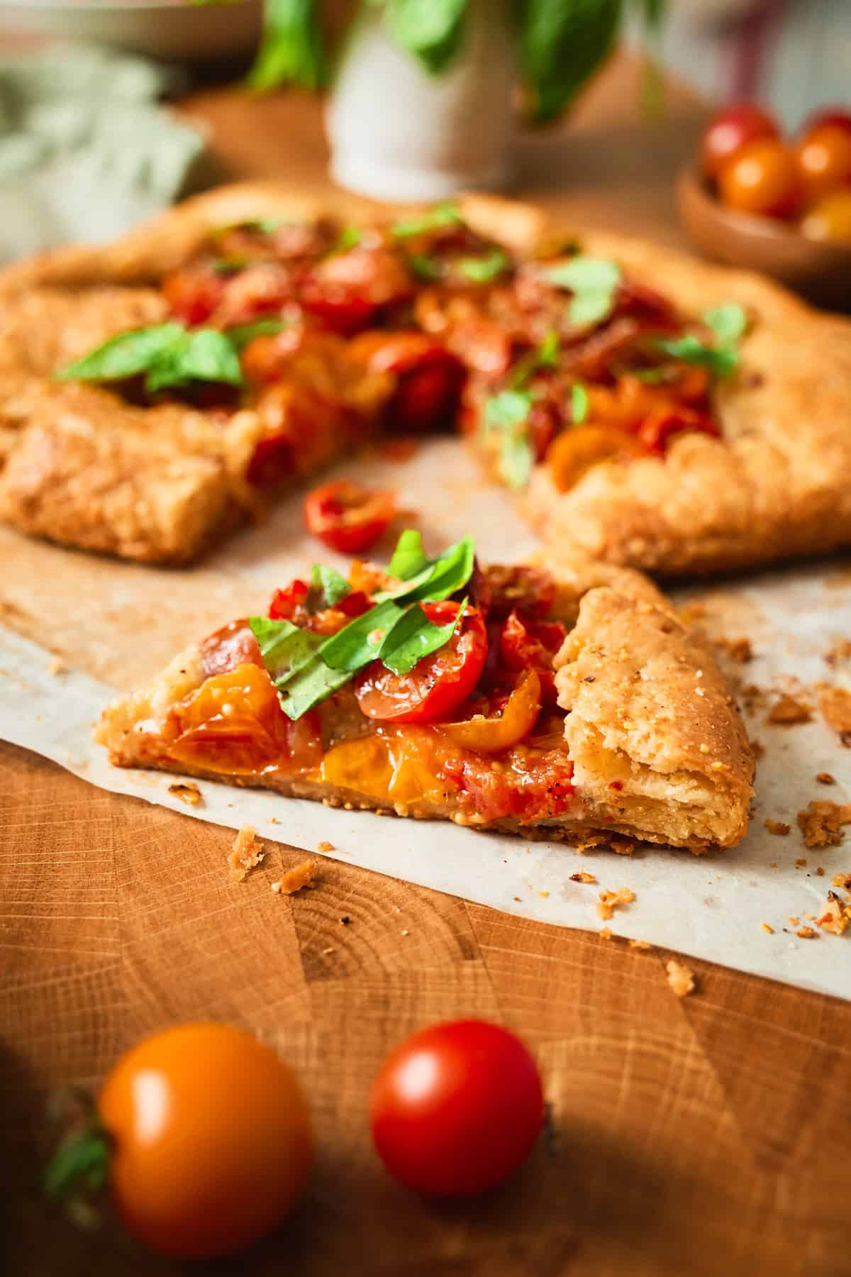 A slice of tomato galette showing the flaky layered crust and roasted cherry tomato filling.