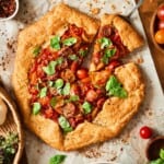 Cherry tomato galette on parchment paper with a slice cut out from overhead.