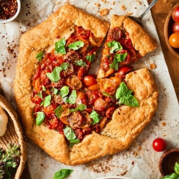 Cherry tomato galette on parchment paper with a slice cut out from overhead.