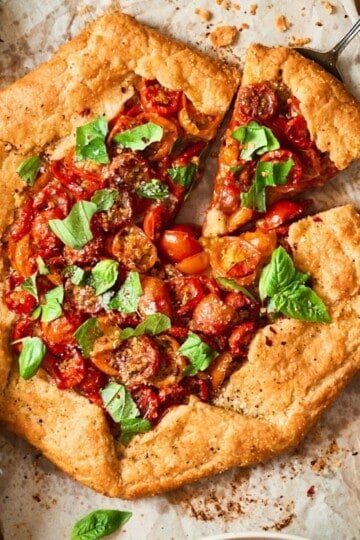 Cherry tomato galette on parchment paper with a slice cut out from overhead.