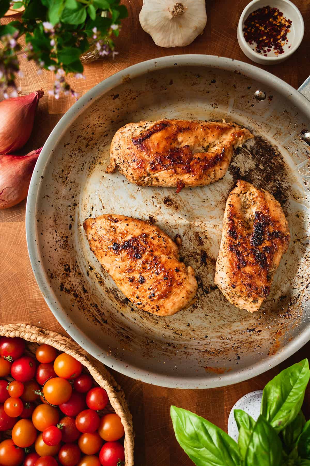 Seared chicken breasts with a golden crust in a stainless skillet.