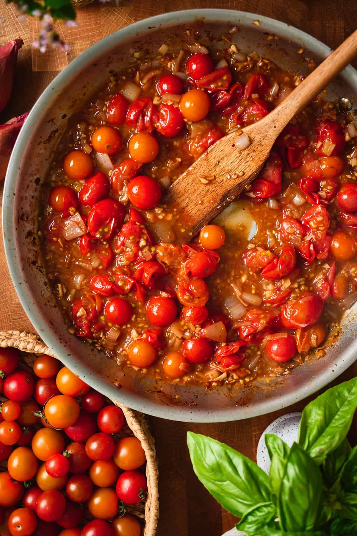 Cherry tomatoes blistering in the skillet, skins splitting and releasing juice.