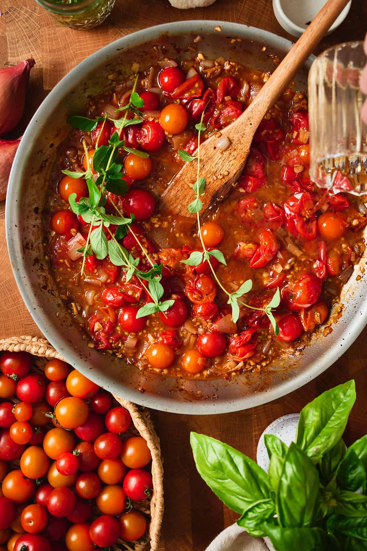 White wine poured into the skillet of burst cherry tomatoes.