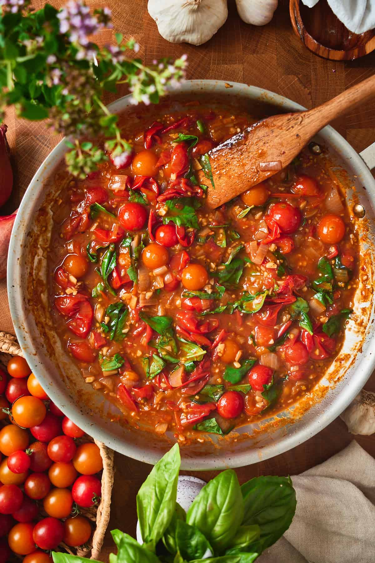 Basil stirred into the glossy burst tomato sauce before the chicken goes back in.