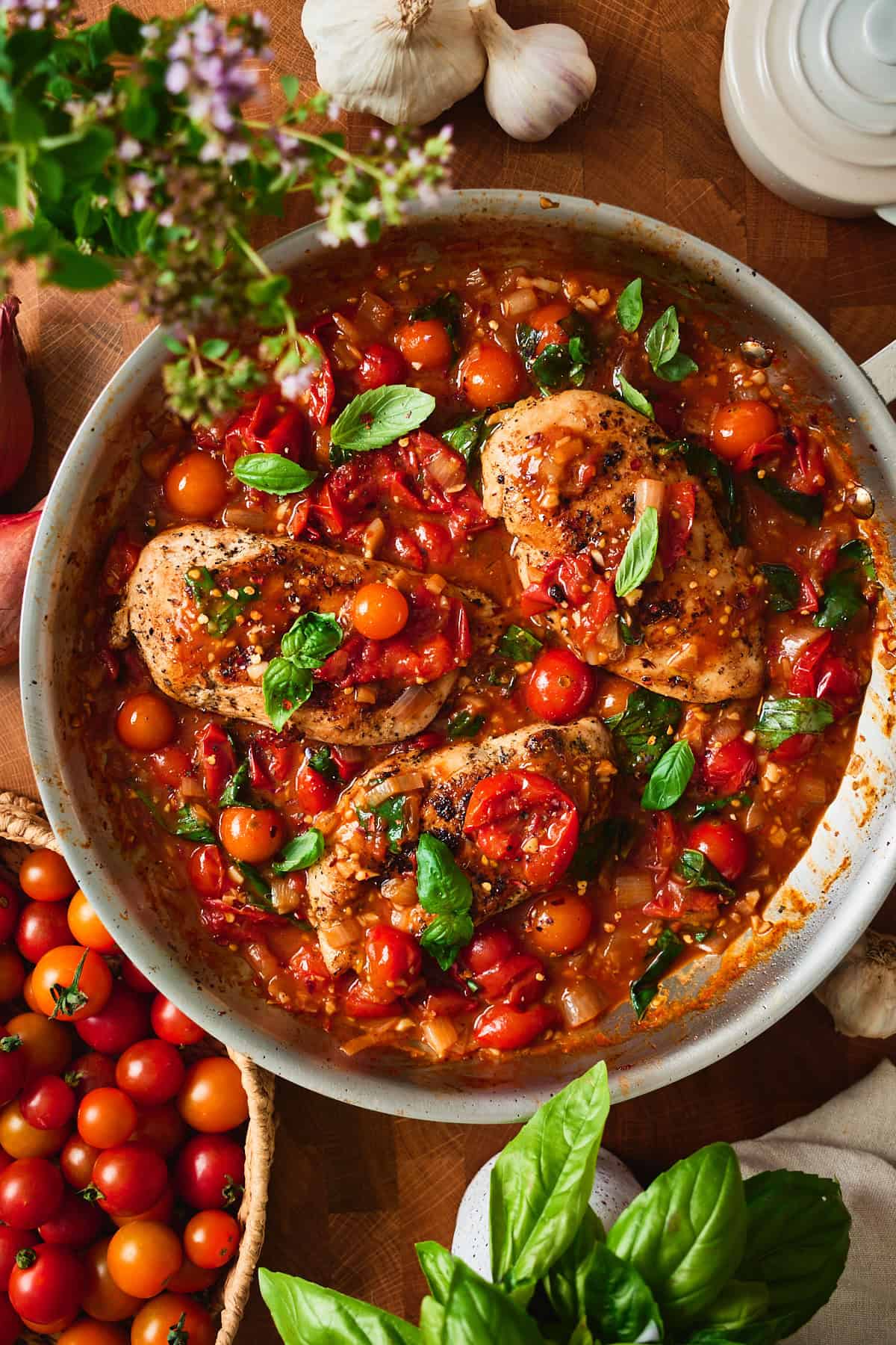 Overhead close-up of chicken pomodoro with basil and burst tomatoes.