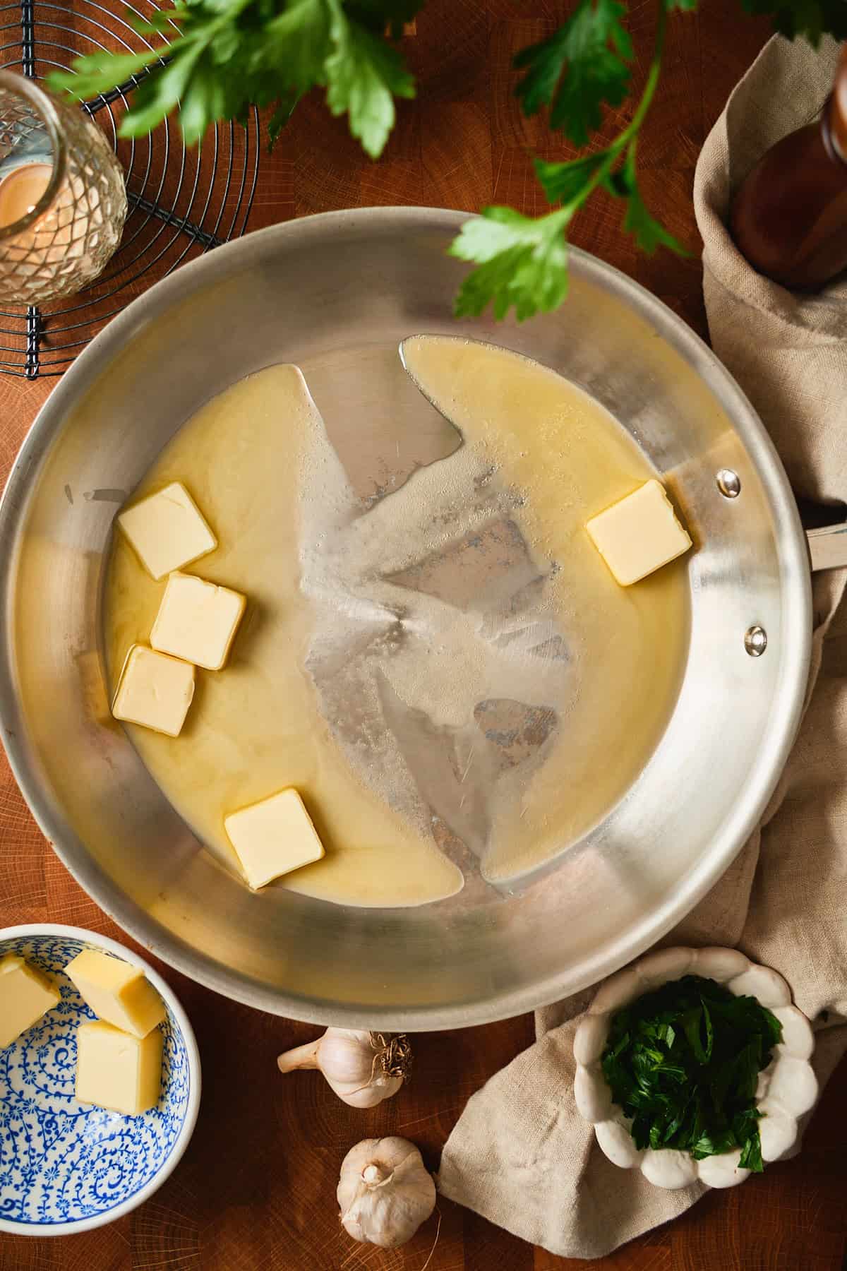 Cubes of butter melting in a wide stainless steel skillet.