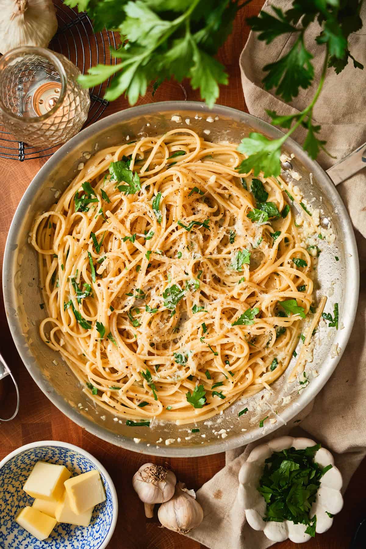 Buttery pasta in a stainless steel skillet with parmesan and parsley.
