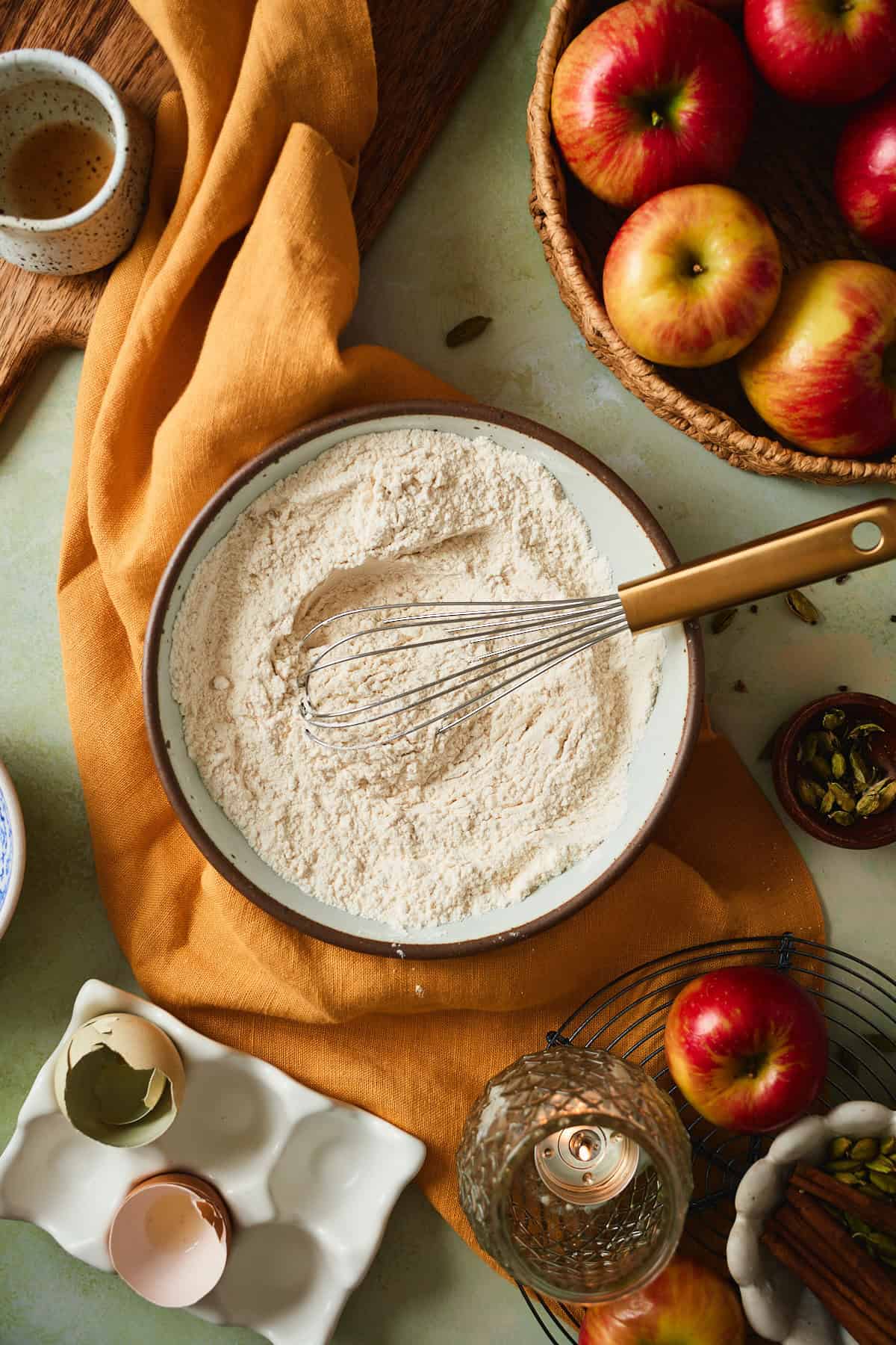 Whisked dry ingredients in a ceramic bowl with a gold-handled whisk.