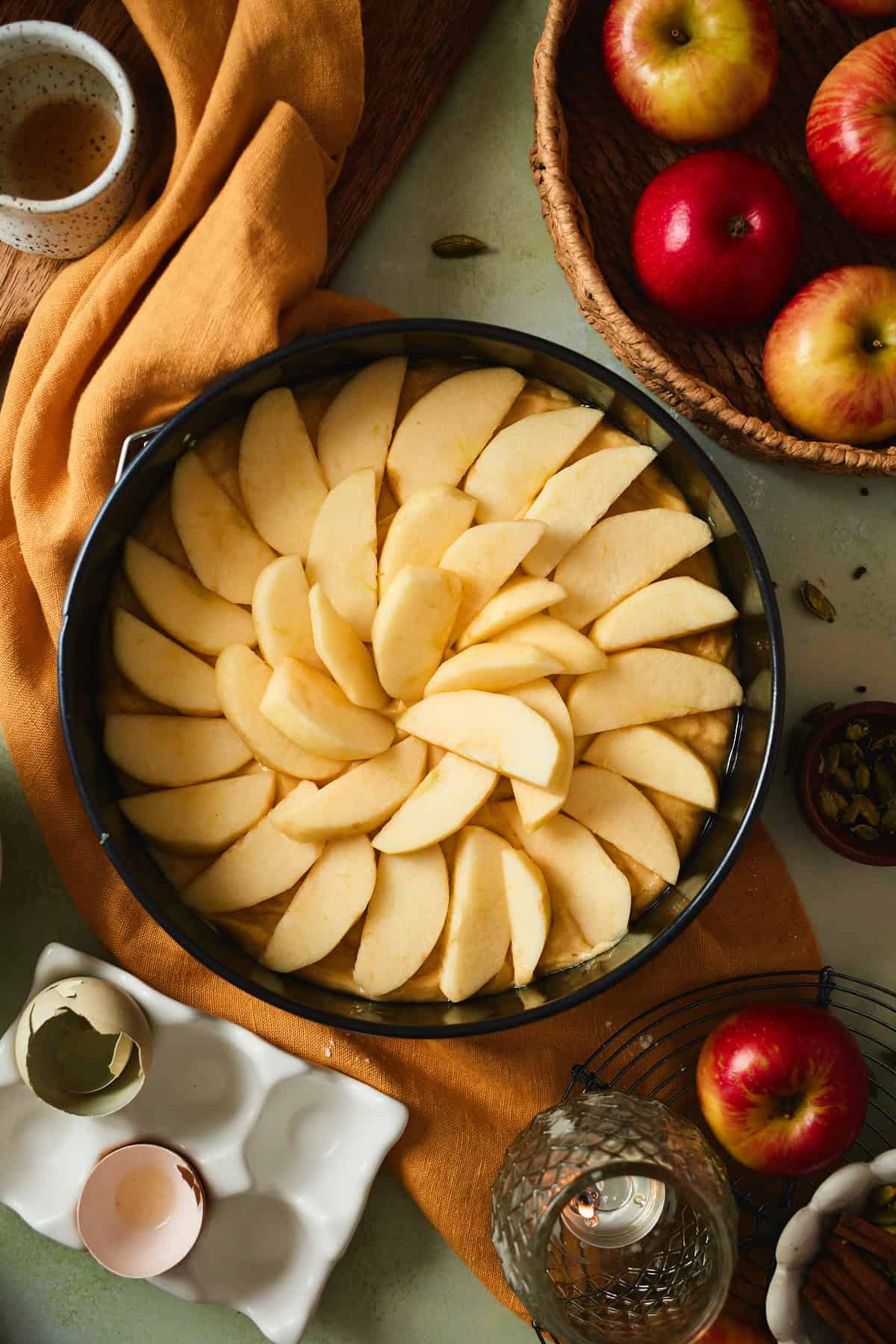Apple wedges pressed into the batter in overlapping circles in a springform pan.