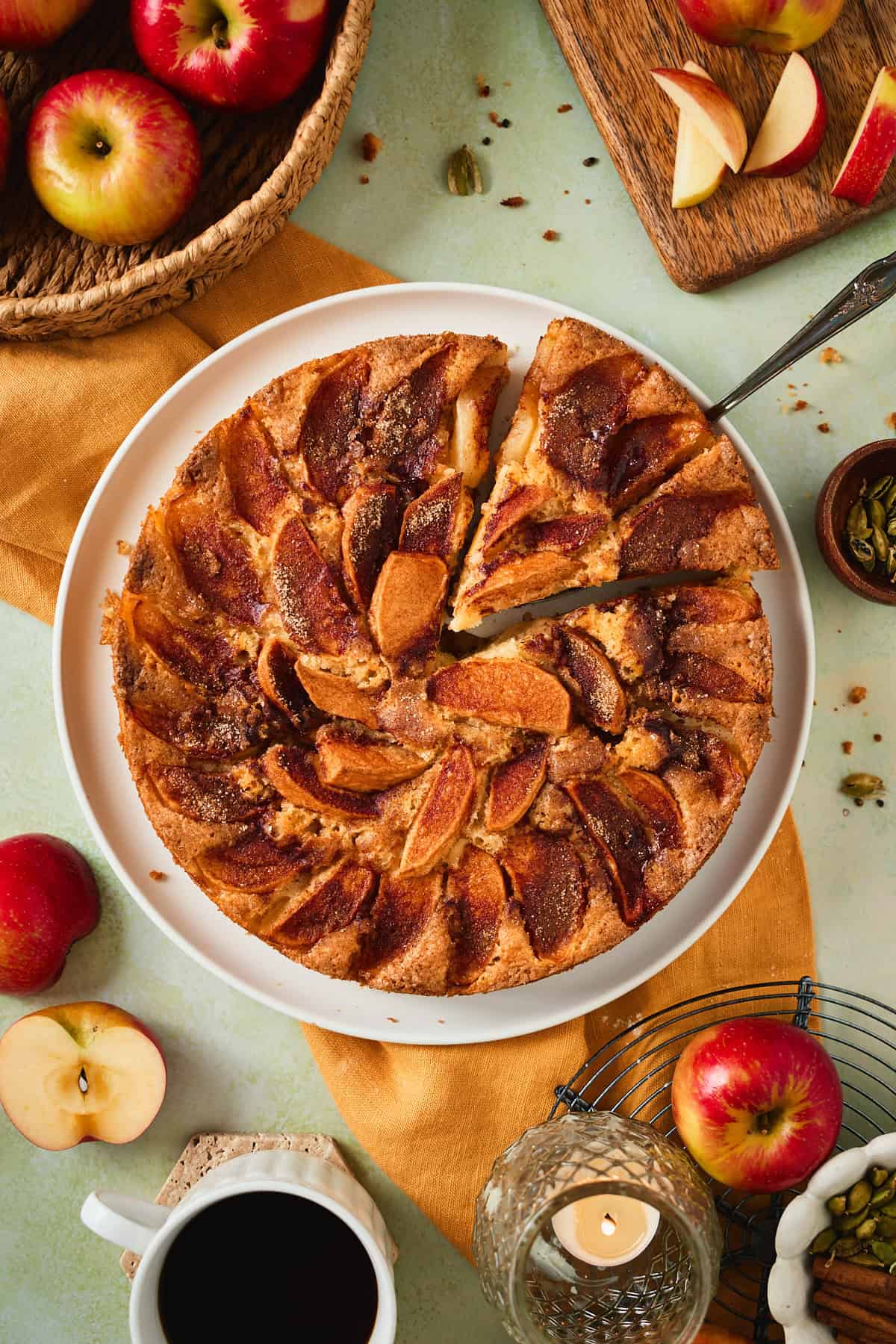 A slice of apple cake lifted from the whole cake with a serving knife.