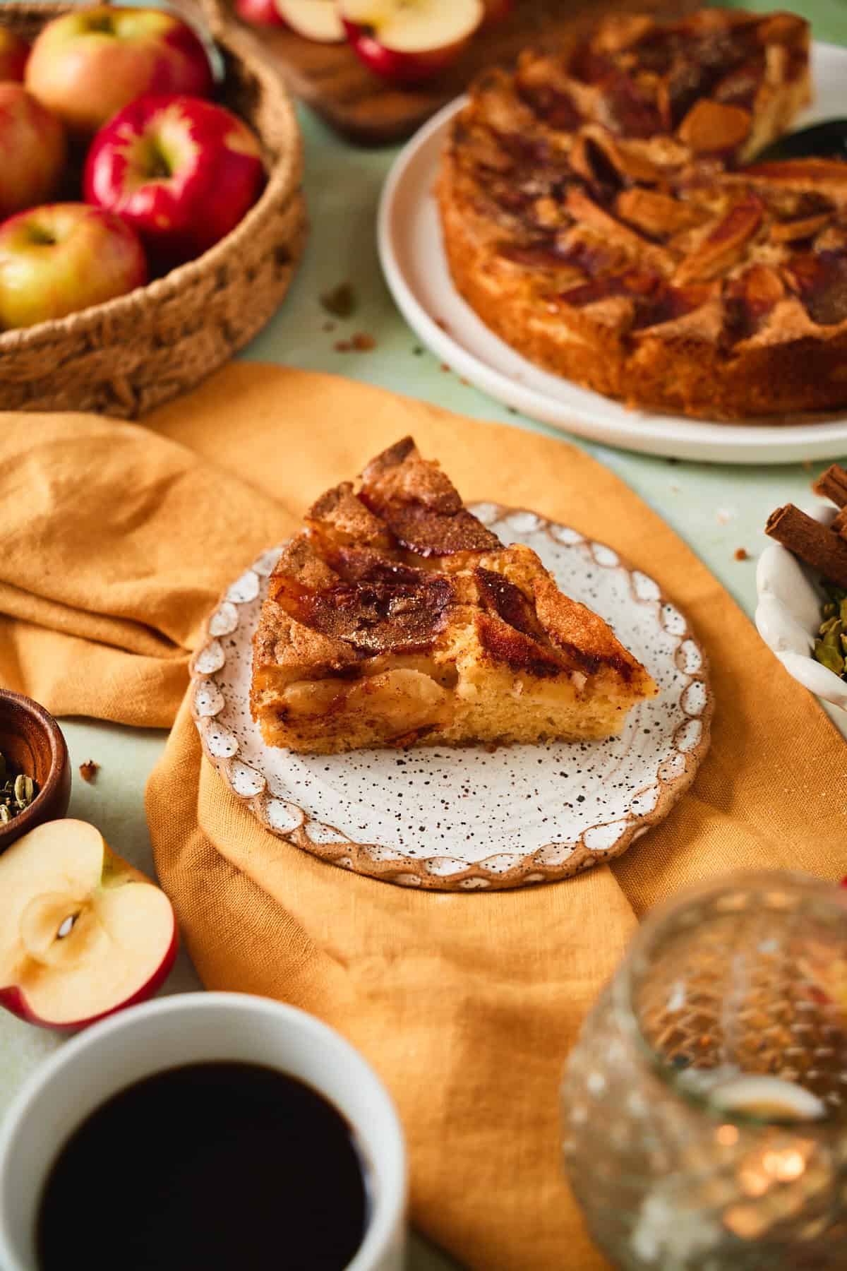 A slice of Swedish apple cake on a speckled plate showing the apple layer and tender crumb.