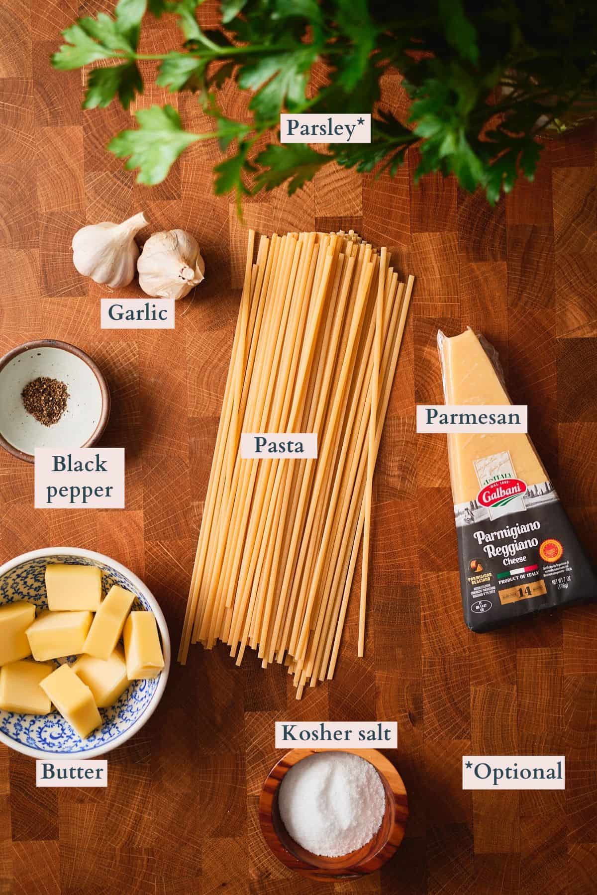 Labeled ingredients for garlic butter pasta including spaghetti, butter, garlic cloves, Parmesan, fresh parsley, kosher salt, and black pepper.