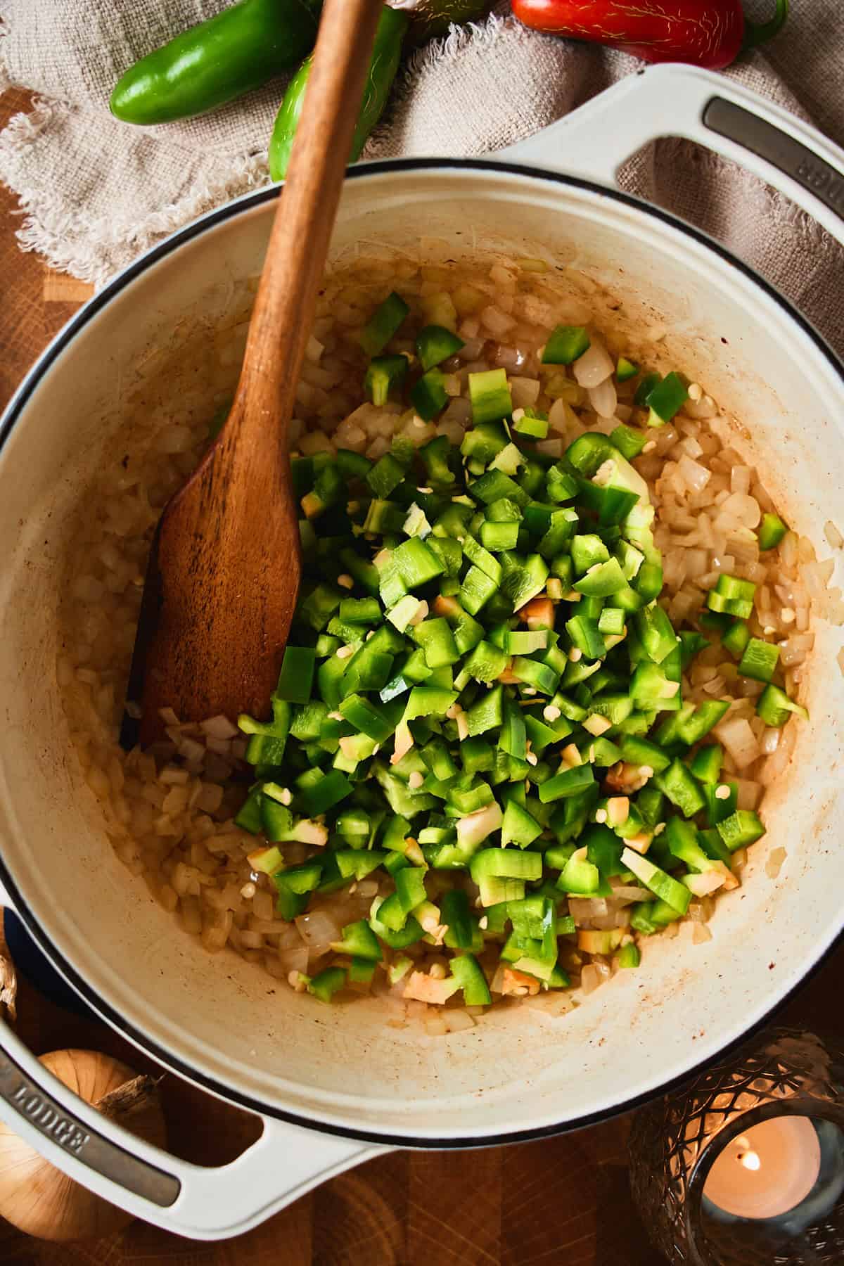 Diced jalapeños with seeds added on top of softened onions in a Dutch oven.