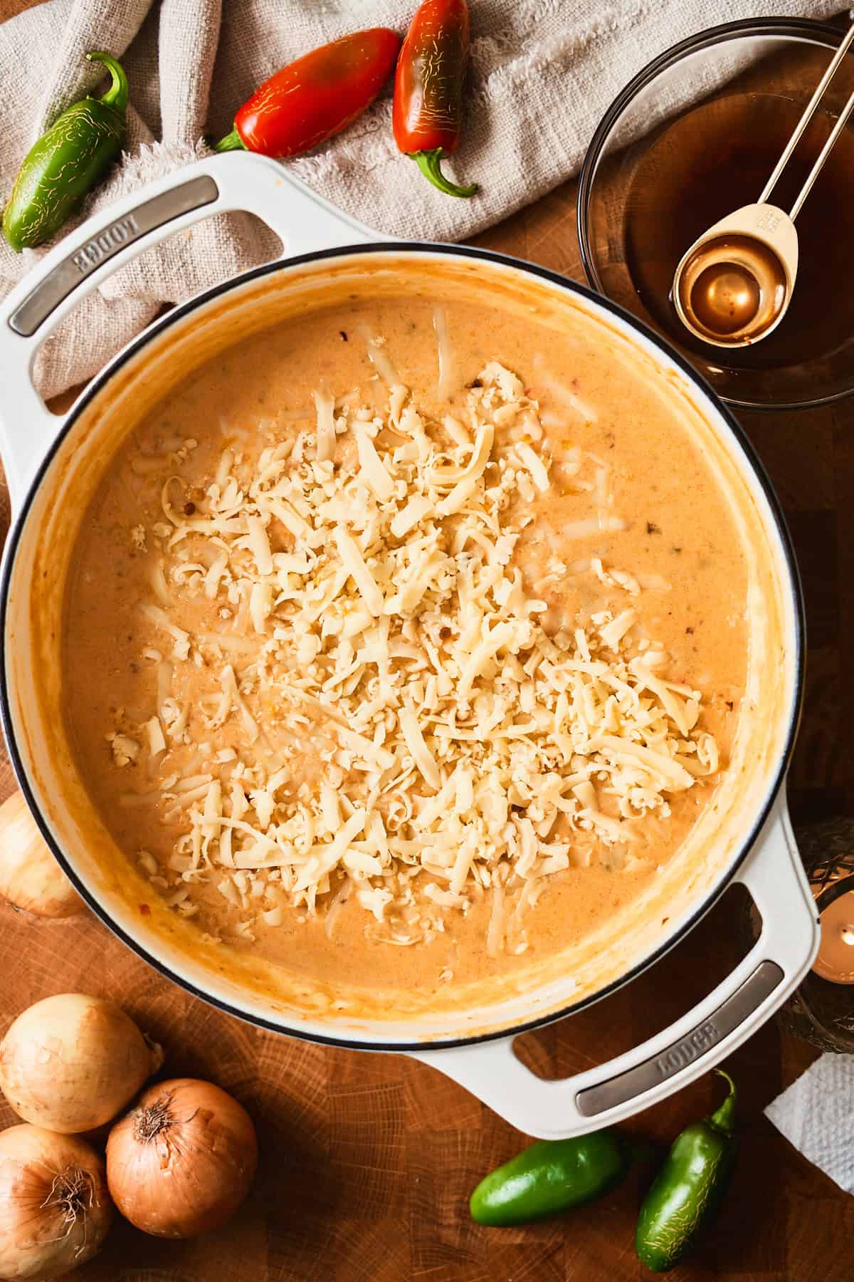 Grated Monterey Jack and pepper jack cheese on top of creamy soup in a Dutch oven.