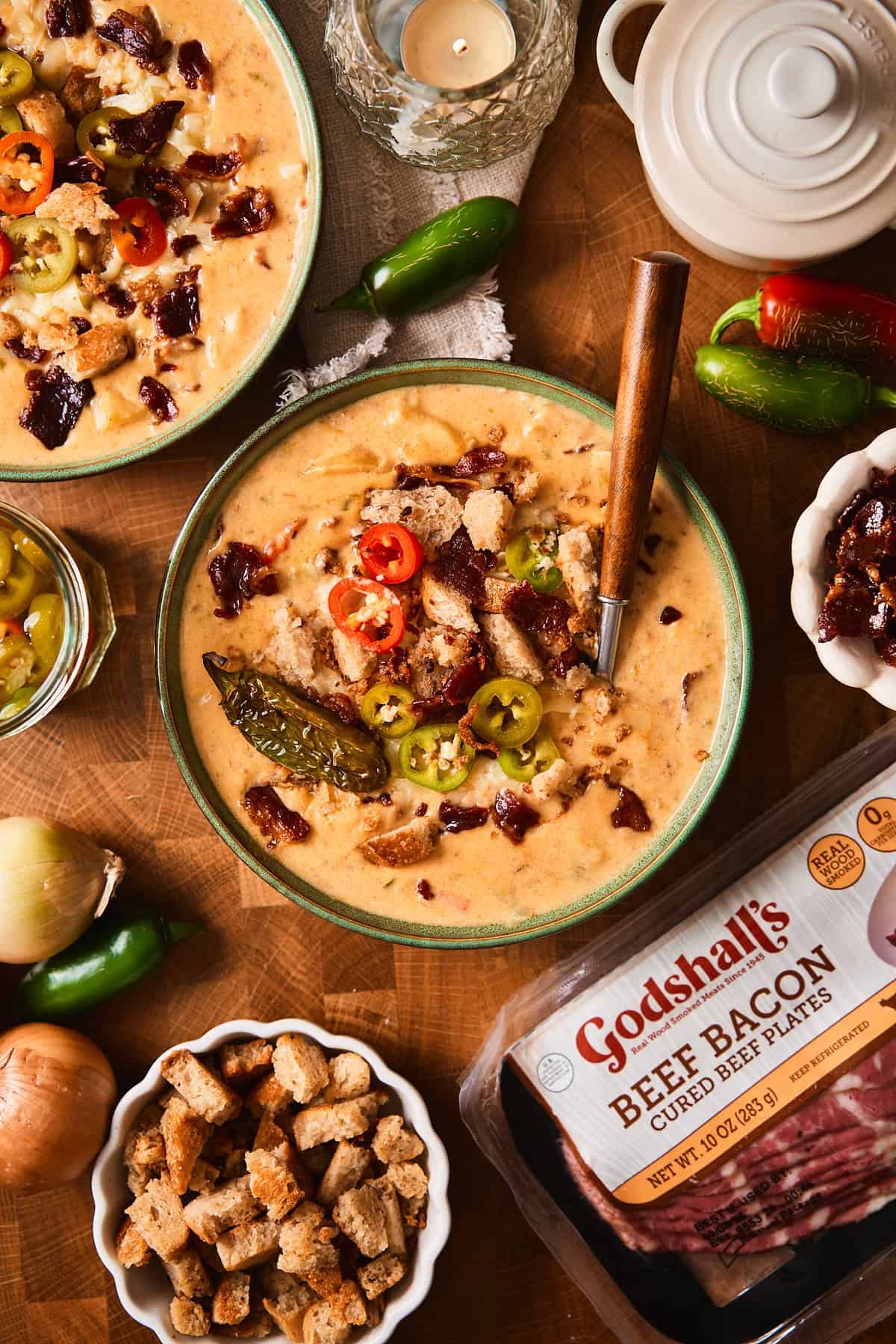 Jalapeño popper soup topped with pickled jalapeños and croutons, next to a package of Godshall's beef bacon.
